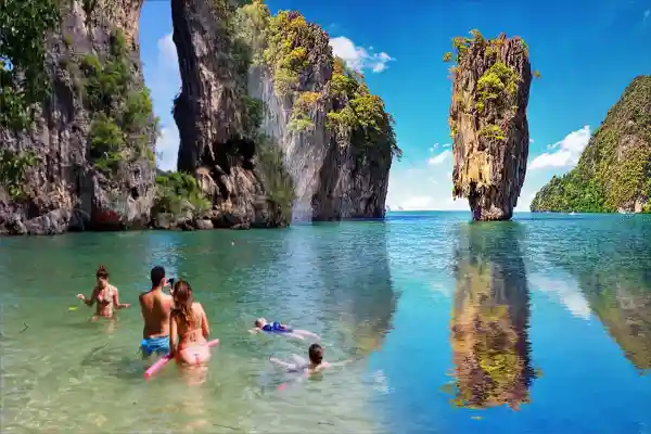 James Bond Island Tour from Phuket with Ko Tapu limestone rock and travelers swimming in Phang Nga Bay