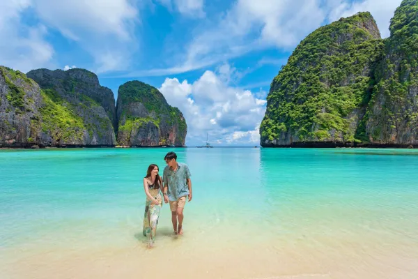 Couple walking on the white-sand beach at Maya Bay during the Phi Phi Island Sunset Tour from Phuket