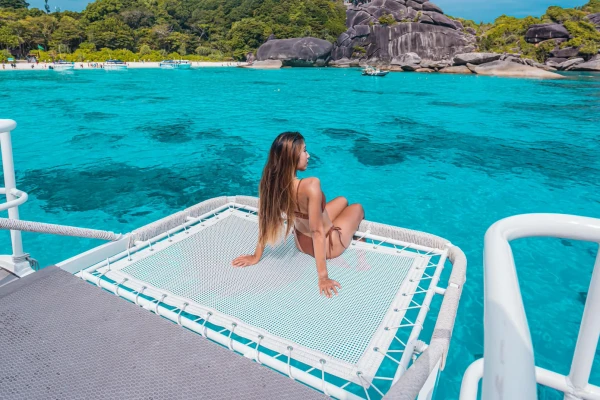 Guest relaxing on the front net of the speed catamaran during the Phi Phi Late Morning Tour