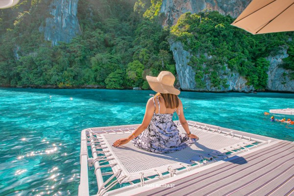 Guest relaxing on the front net during the Phi Phi Island Late Morning Tour by speed catamaran
