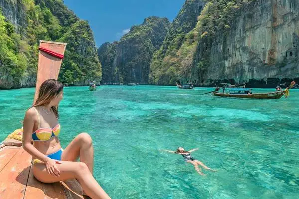 Swimming and long-tail boat scenery at Pileh Lagoon during the Phi Phi Island Sunset Tour from Phuket