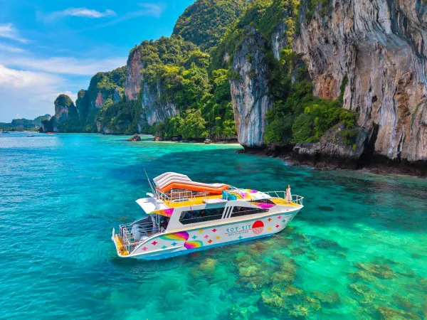 Speed catamaran cruising beside limestone cliffs in the Phi Phi Islands