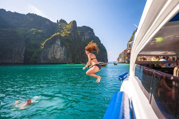 Traveler jumping from a speedboat into clear lagoon water during the Phi Phi Island Sunset Tour from Phuket