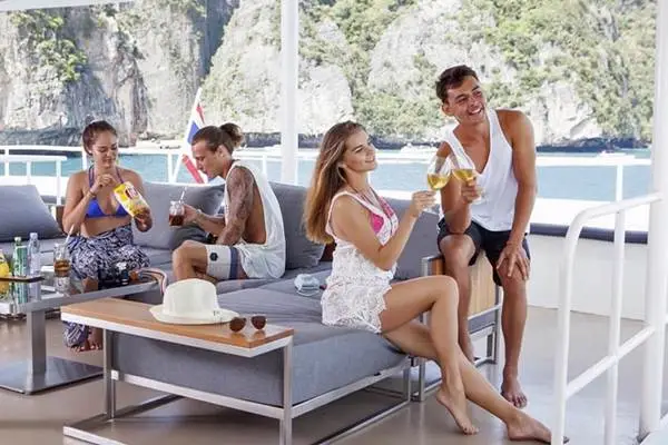 Travelers relaxing with drinks on the open deck during a Phi Phi Island tour by cruise from Phuket