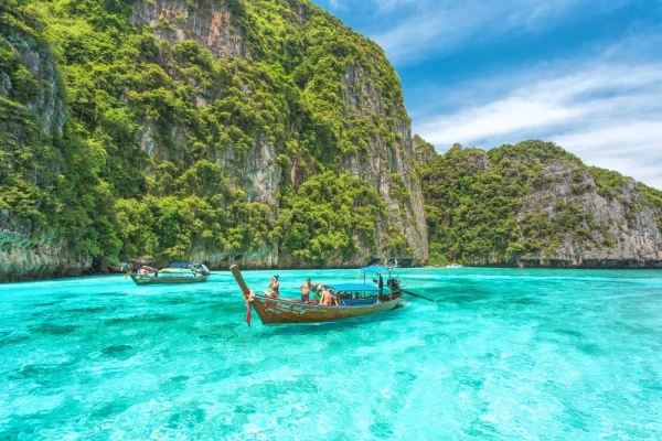 Traditional long-tail boat cruising through the turquoise water of Pileh Lagoon