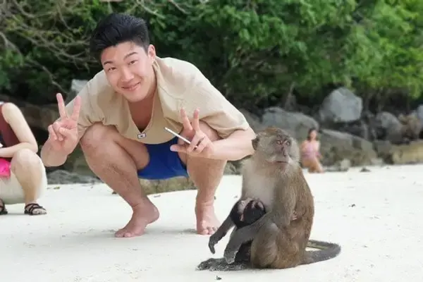 Traveler observing a wild macaque at Monkey Beach during a Phi Phi Island tour