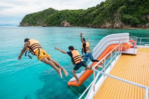 Travelers jumping from the speed catamaran into clear tropical water near Maiton Island