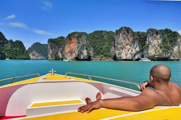 Passenger relaxing on a speedboat while sightseeing limestone cliffs near Khao Khian in Phang Nga Bay