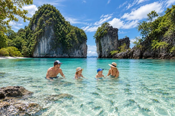Family relaxing in clear turquoise water at Hong Island Krabi during a tour from Phuket