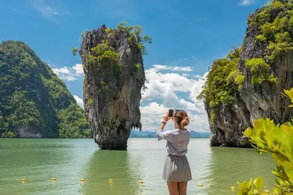 Tourist photographing Khao Tapu at James Bond Island during the late morning tour from Phuket