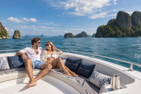 European couple relaxing on the bow of a luxury power catamaran cruising through Phang Nga Bay
