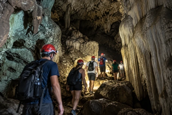 Small group of tourists exploring a limestone cave in Phang Nga Bay during the James Bond Island Sunrise Tour from Phuket