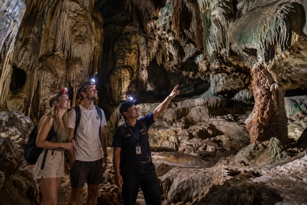 European couple exploring a limestone cave with a Thai guide during the James Bond Island Sunrise Tour from Phuket