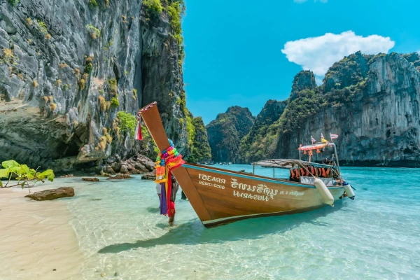Traditional long-tail boat surrounded by limestone cliffs at Phi Phi Island