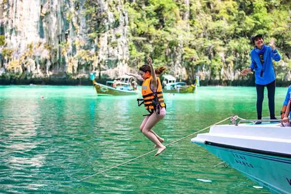 Traveler jumping into turquoise water during a Phi Phi Island and Bamboo Island speedboat tour from Phuket