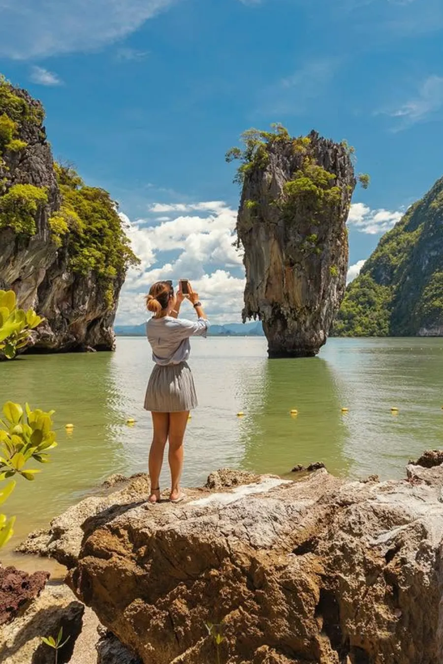 Tourist photographing Khao Tapu, the famous James Bond Island limestone landmark in Phang Nga Bay, Thailand