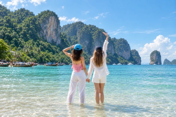 Two travelers enjoying clear turquoise water and limestone scenery at Phi Phi Island during a cruise tour from Phuket