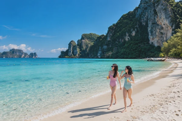Two travelers walking on a tropical beach at Phi Phi Don during a Phi Phi Island cruise tour from Phuket