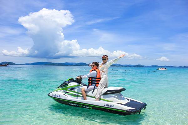Jet ski activity in clear tropical water near an island beach in Phuket
